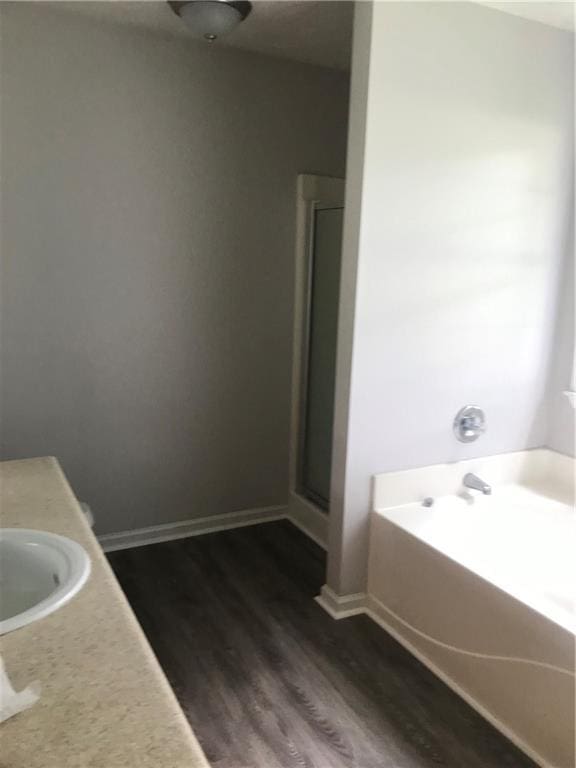 75 Oak Hill Dr, Covington, GA 30016 - full bathroom with wood finished floors, a garden tub, a shower stall, baseboards, and vanity