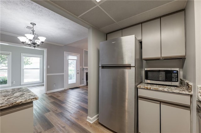 kitchen featuring appliances with stainless steel finishes, a chandelier, light wood-style floors, baseboards, and hanging light fixtures