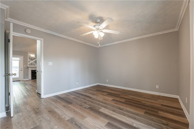 unfurnished room featuring a textured ceiling, ceiling fan, wood finished floors, baseboards, and ornamental molding