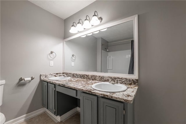 full bath with toilet, double vanity, tile patterned floors, and baseboards