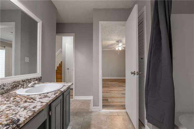 full bath featuring a textured ceiling, a ceiling fan, tile patterned floors, vanity, and baseboards