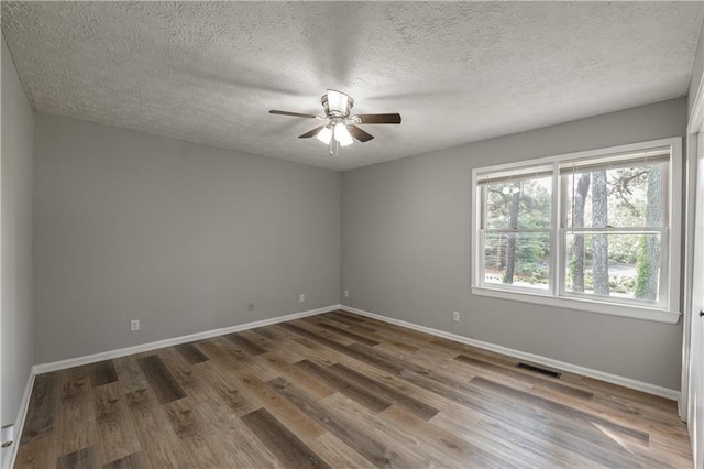 empty room with a ceiling fan, wood finished floors, baseboards, and a textured ceiling
