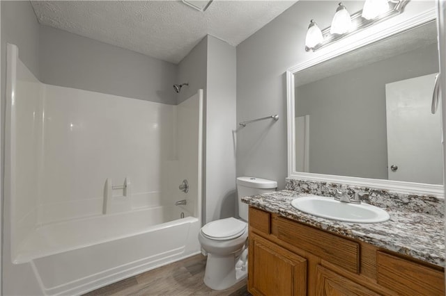 full bath with wood finished floors, toilet, a textured ceiling, tub / shower combination, and vanity