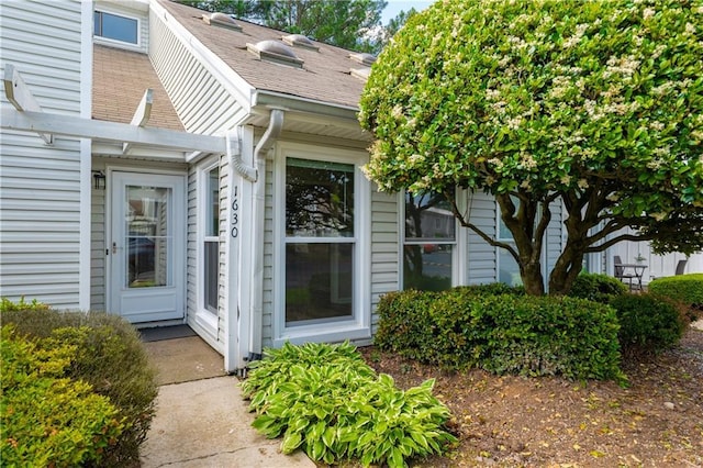 doorway to property with a shingled roof