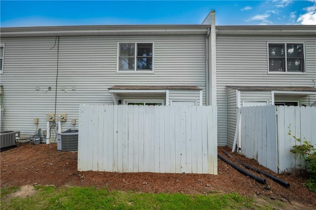 back of property with central AC unit and fence