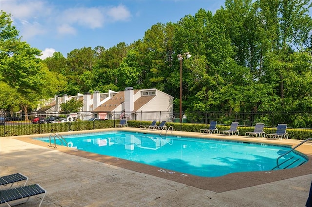 community pool with a patio area and fence