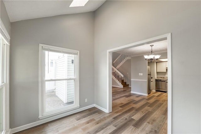 foyer entrance with stairway, a chandelier, wood finished floors, baseboards, and high vaulted ceiling