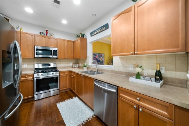 kitchen with appliances with stainless steel finishes, dark hardwood / wood-style floors, sink, and backsplash