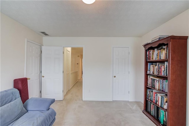 sitting room with light carpet, baseboards, and a textured ceiling