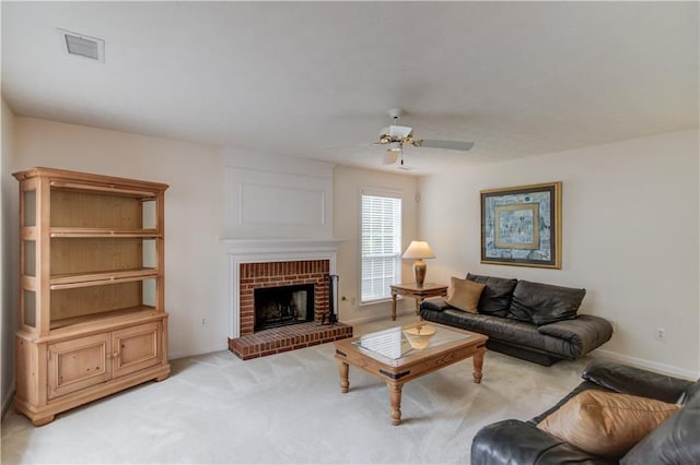 living area with ceiling fan, light colored carpet, a fireplace, and baseboards