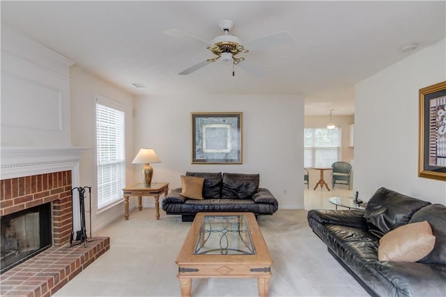 living room with light carpet, ceiling fan, a brick fireplace, and baseboards