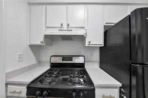 kitchen featuring stainless steel gas range, under cabinet range hood, white cabinetry, and light countertops