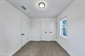 empty room featuring dark wood-style floors, visible vents, and baseboards