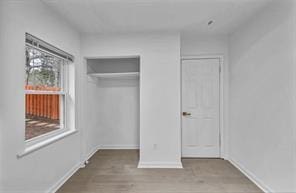 unfurnished bedroom with a closet, baseboards, and wood finished floors