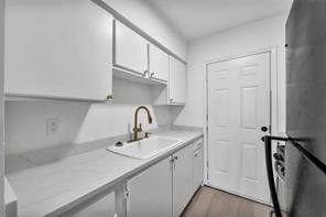 kitchen featuring wood finished floors, a sink, white cabinets, light countertops, and freestanding refrigerator