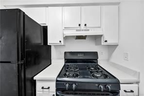 kitchen with black appliances, under cabinet range hood, white cabinetry, and light countertops