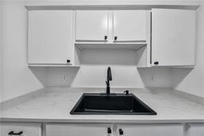 kitchen featuring white cabinets, a sink, and light countertops