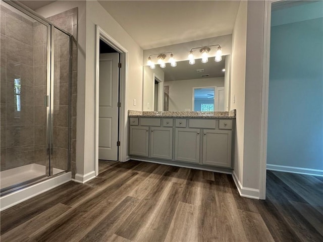 bathroom with vanity, a shower stall, wood finished floors, and baseboards