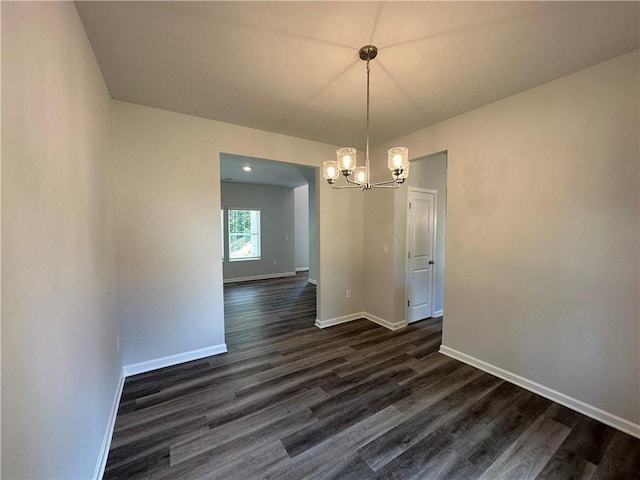 unfurnished dining area featuring baseboards, dark wood-type flooring, and an inviting chandelier