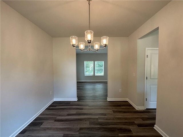 unfurnished dining area with an inviting chandelier, dark wood-style floors, and baseboards