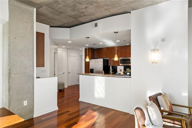 kitchen featuring kitchen peninsula, appliances with stainless steel finishes, dark hardwood / wood-style floors, stone counters, and pendant lighting