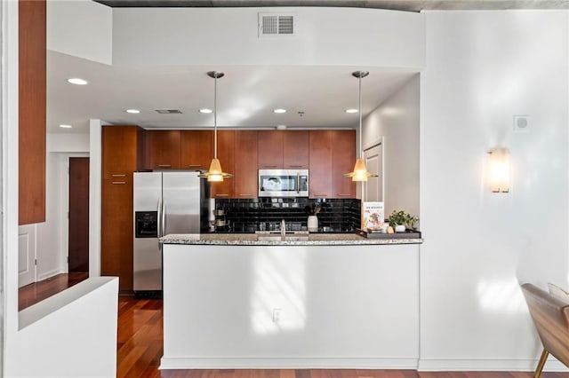 kitchen featuring pendant lighting, wood-type flooring, sink, appliances with stainless steel finishes, and light stone counters