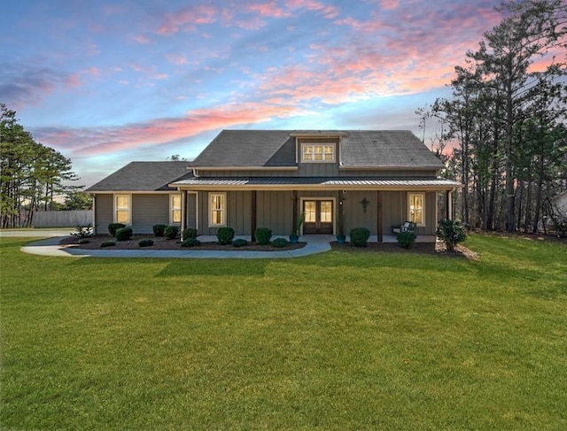 view of front facade featuring covered porch, a standing seam roof, board and batten siding, and a front yard