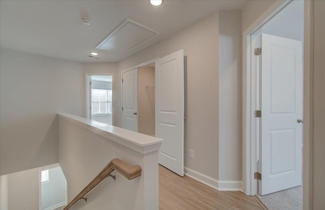 hallway with light wood finished floors, recessed lighting, attic access, an upstairs landing, and baseboards