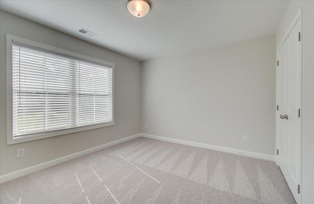 empty room with carpet, visible vents, and baseboards