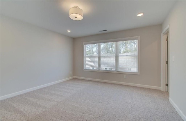 empty room with recessed lighting, light carpet, visible vents, and baseboards