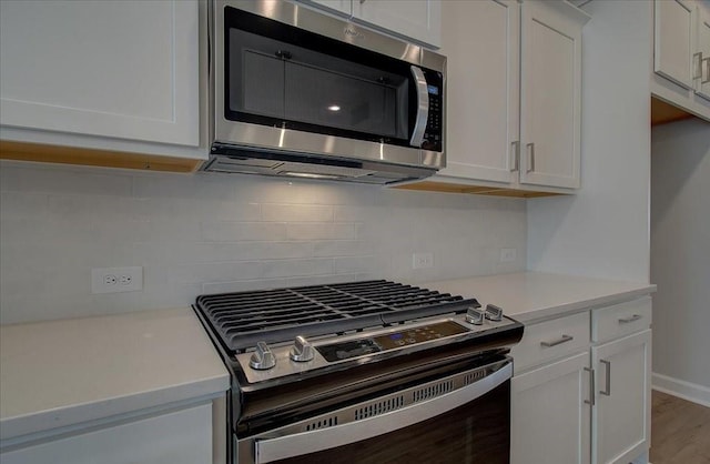 kitchen featuring tasteful backsplash, wood finished floors, stainless steel appliances, light countertops, and white cabinetry