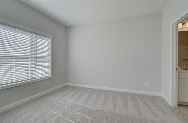 unfurnished room featuring light carpet and baseboards