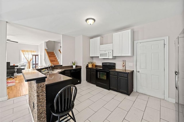 kitchen featuring white cabinetry, kitchen peninsula, sink, and black appliances