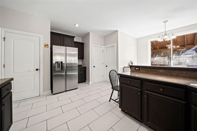 kitchen featuring a kitchen breakfast bar, stainless steel fridge, decorative light fixtures, and a notable chandelier