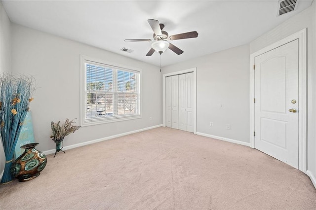 unfurnished bedroom featuring light colored carpet, ceiling fan, and a closet