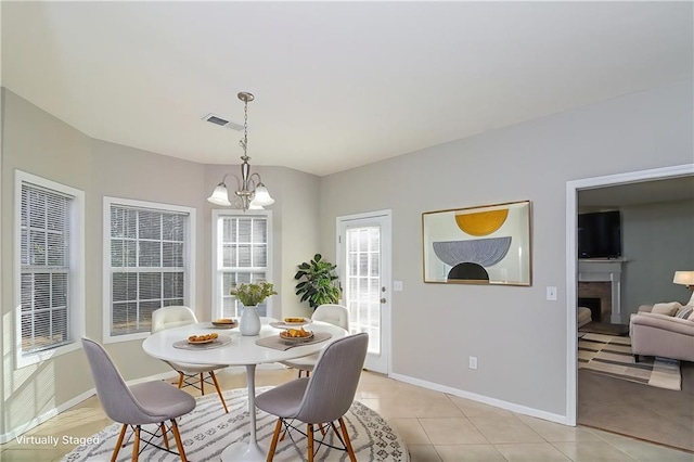 122 Melrose Creek Dr, Stockbridge, GA 30281 - dining space featuring baseboards, light tile patterned floors, a fireplace, and a chandelier