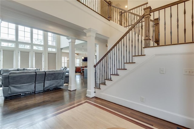 entryway featuring wood-type flooring, a high ceiling, and decorative columns