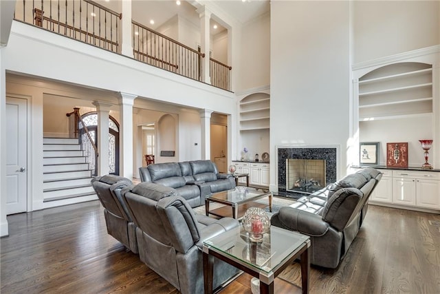 living room with ornate columns, dark hardwood / wood-style floors, and a high ceiling