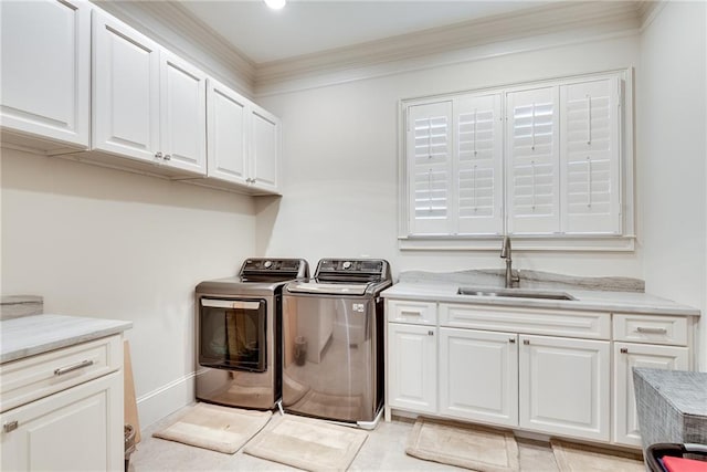 laundry room with ornamental molding, sink, washing machine and clothes dryer, and cabinets