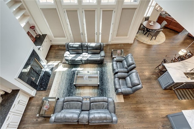 living room featuring a towering ceiling, a high end fireplace, and dark wood-type flooring