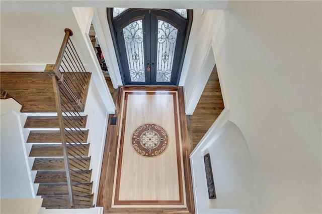 foyer entrance with french doors, hardwood / wood-style flooring, and a towering ceiling