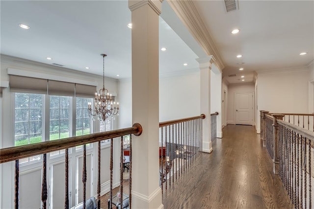 hall featuring ornamental molding, decorative columns, dark hardwood / wood-style floors, and a chandelier