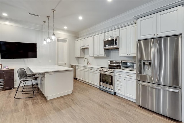 kitchen with a breakfast bar area, white cabinets, appliances with stainless steel finishes, light stone counters, and light hardwood / wood-style floors