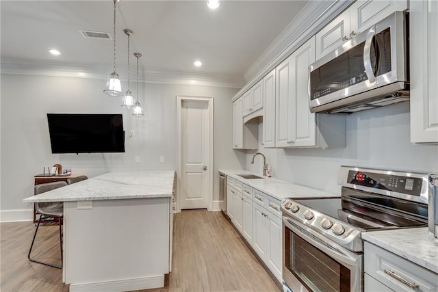 kitchen featuring white cabinets, hanging light fixtures, appliances with stainless steel finishes, a breakfast bar, and light wood-type flooring