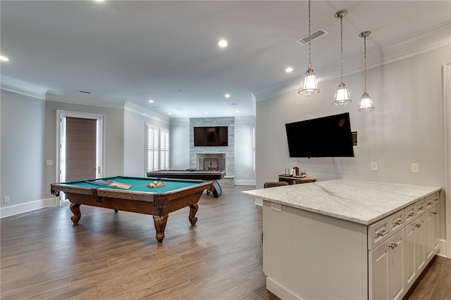 recreation room with a stone fireplace, ornamental molding, light hardwood / wood-style flooring, and pool table