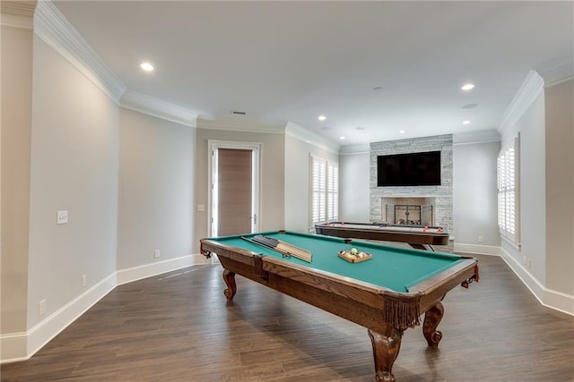 rec room with ornamental molding, a stone fireplace, and dark hardwood / wood-style flooring