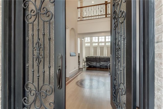 entrance foyer featuring ornate columns, a high ceiling, and hardwood / wood-style floors