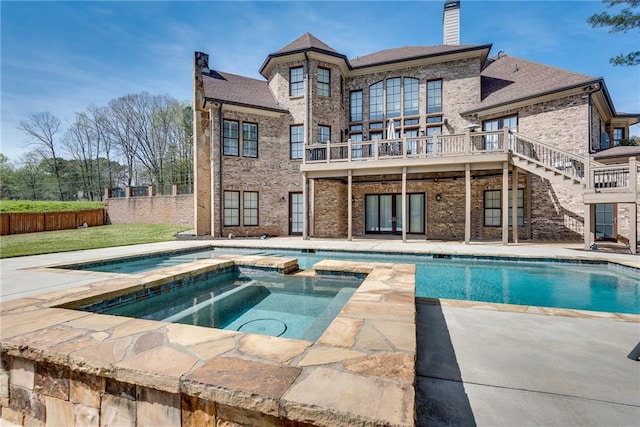 back of house with a patio area and a pool with hot tub