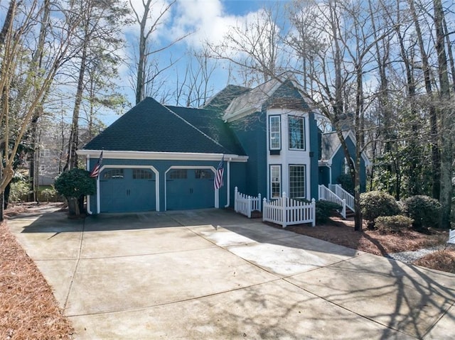 view of side of home with roof with shingles, driveway, an attached garage, and fence