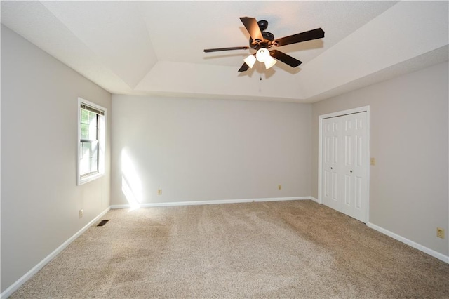 spare room featuring ceiling fan, a raised ceiling, and carpet flooring